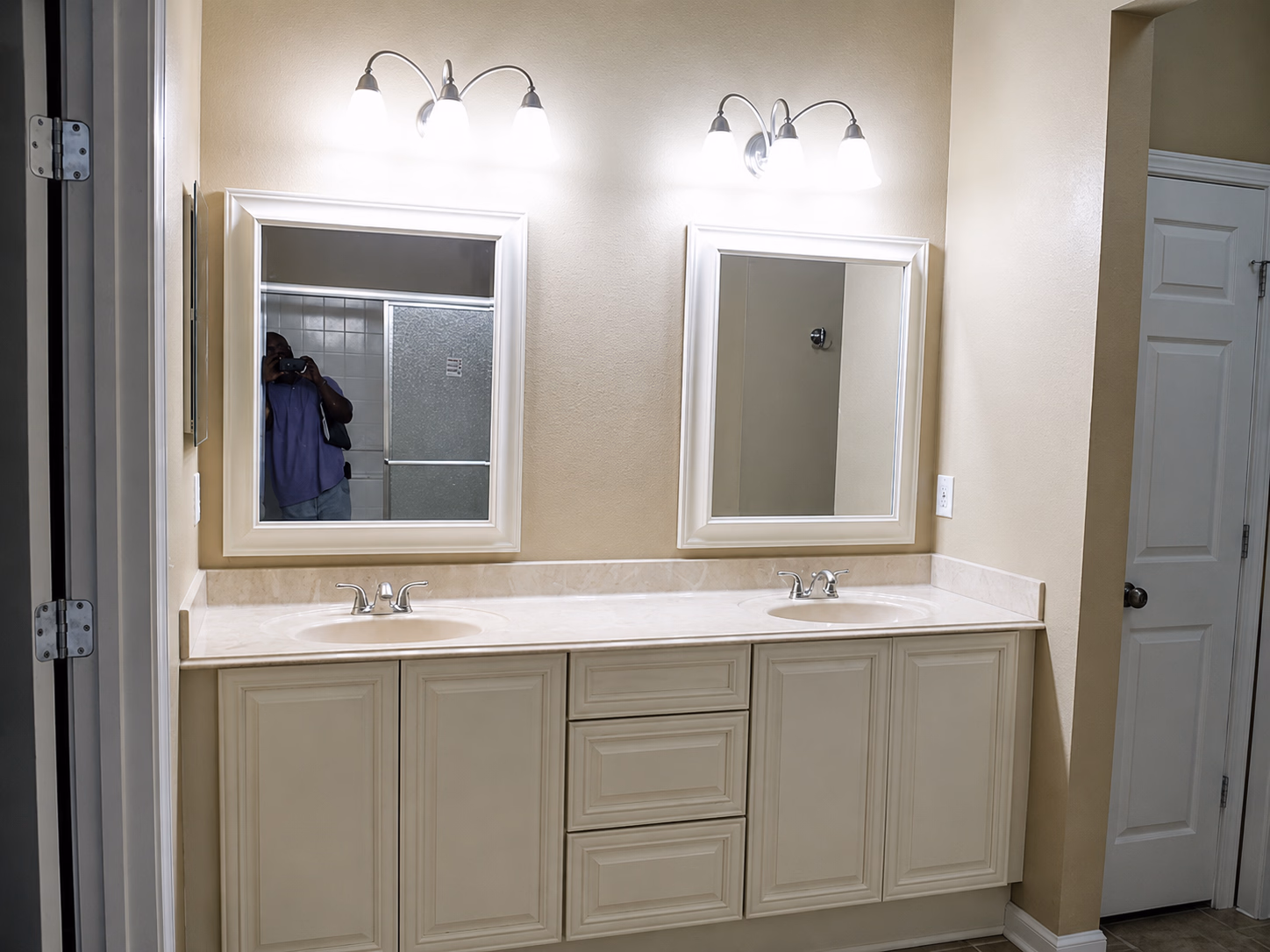 Bathroom vanity with two sinks, two mirrors, and three-light wall fixtures above each mirror.